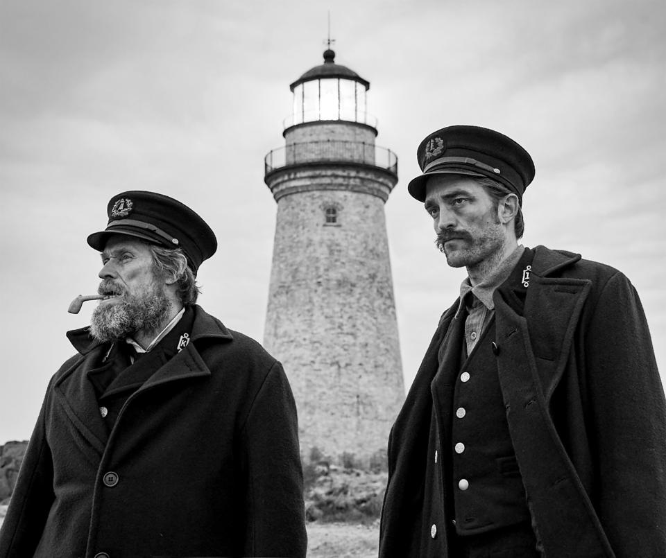 Willem Dafoe and Robert Pattison stand outside a lighthouse