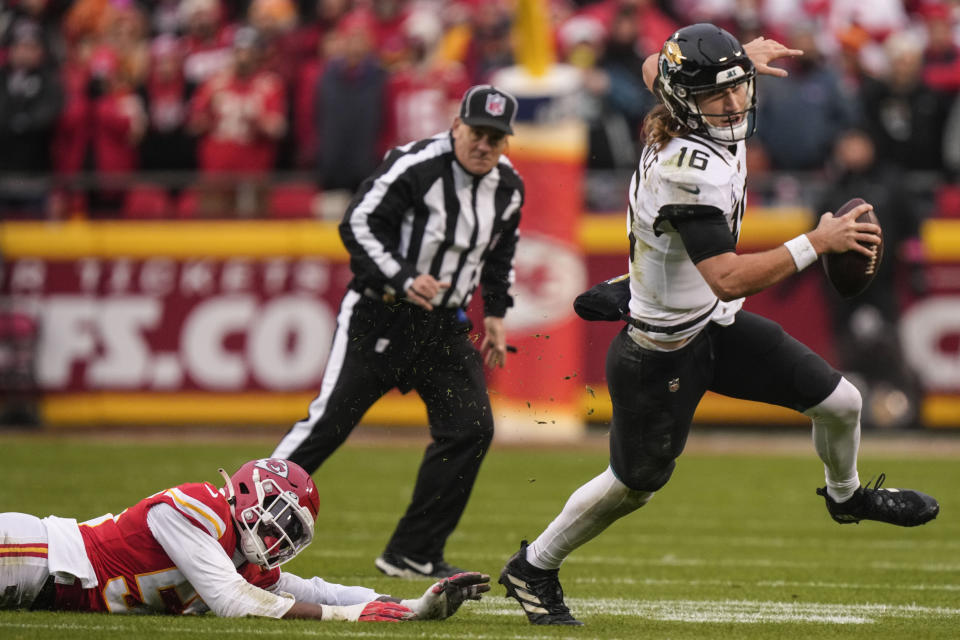 Jacksonville Jaguars quarterback Trevor Lawrence (16) runs past Kansas City Chiefs defensive end Frank Clark (55) during the first half of an NFL divisional round playoff football game, Saturday, Jan. 21, 2023, in Kansas City, Mo. (AP Photo/Charlie Riedel)