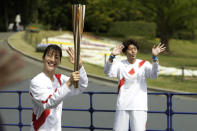 Former Olympian Aya Terakawa, participating as an Olympic torch relay runner, waves as she starts carrying the torch during the first day of the Osaka round at a former Expo site in Suita, north of Osaka, western Japan, Tuesday, April 13, 2021. The Tokyo 2020 Olympic kick-off event which was rescheduled due to the coronavirus outbreak was yet rearranged to hold at the former Expo park, instead of public streets, to close off the audience from the even, following the mayor's decision as Osaka has had sharp increases in daily cases since early March. (AP Photo/Hiro Komae)