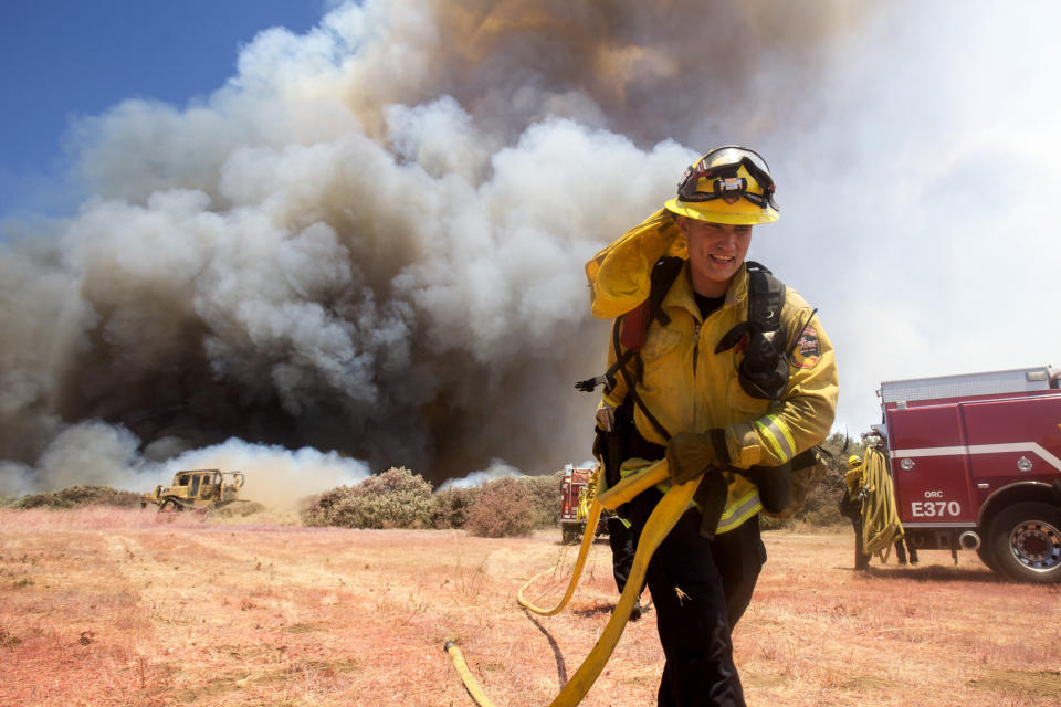 A firefighter battles a brush fire at the Apple Fire in Cherry Valley, Calif., Saturday, Aug. 1, 2020. A wildfire northwest of Palm Springs flared up Saturday afternoon, prompting authorities to issue new evacuation orders as crews fought the blaze in triple-degree heat. The blaze began as two separate fires Friday evening in Cherry Valley, an unincorporated area near the city of Beaumont in Riverside County. (AP Photo/Ringo H.W. Chiu)