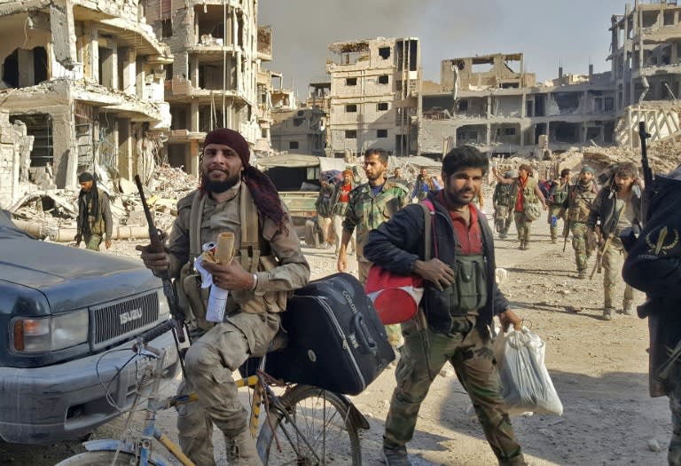 Syrian pro-government forces are seen in front of damaged buildings in the eastern city of Deir Ezzor on November 3, 2017