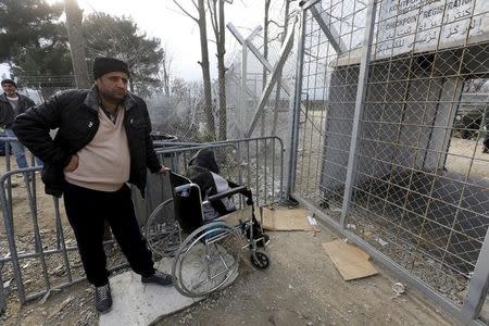 Stranded wheelchair-bound Zhino Hasan, 17, and her father Sarkawt wait in front of a closed border gate at Idomeni, hoping that Macedonia would relent and allow her and her family to resume their northward trek through the Balkans to Germany, February 26, 2016. REUTERS/Yannis Behrakis