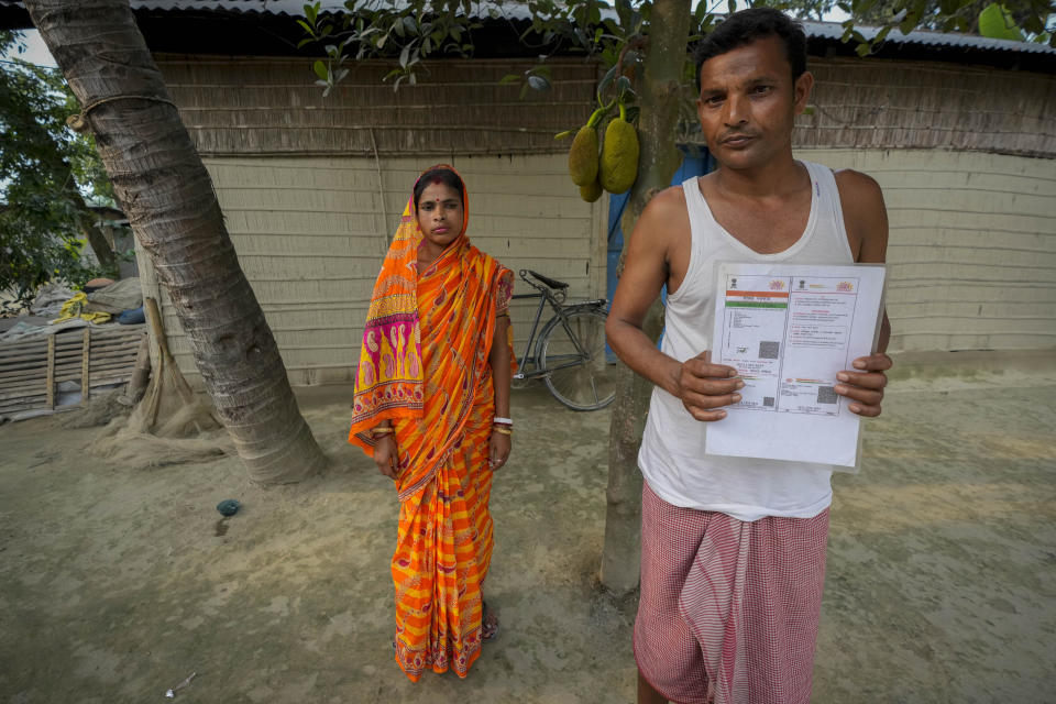 Krishna Biswas, 35, who has not been able to prove his Indian citizenship, shows his Aadhaar card, as his wife Dipali Biswas, 30, stands by outside their house in Murkata village, north eastern Assam state, India, April 15, 2023. Millions of people like Biswas, whose citizenship status is unclear, were born in India to parents who immigrated many decades ago. Nearly 2 million people, or over 5% of Assam's population, could be stripped of their citizenship unless they have documents dating back to 1971 that show their ancestors entered the country legally from neighboring Bangladesh. (AP Photo/Anupam Nath)