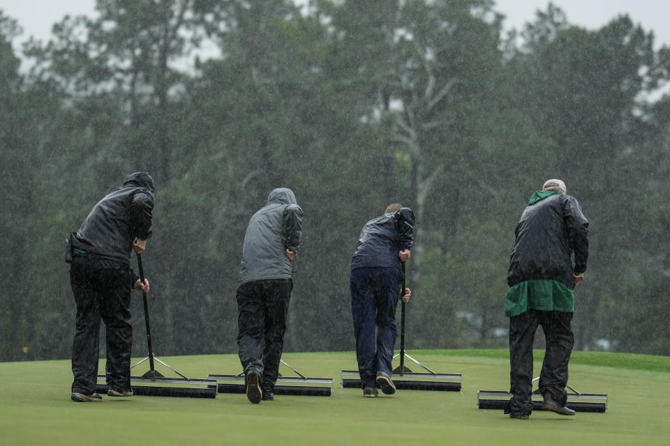 Members of the grounds crew squeegee the green on the 18th hole during the weather delayed second round of the Masters golf tournament at Augusta National Golf Club on Saturday, April 8, 2023, in Augusta, Ga. (AP Photo/Charlie Riedel)
