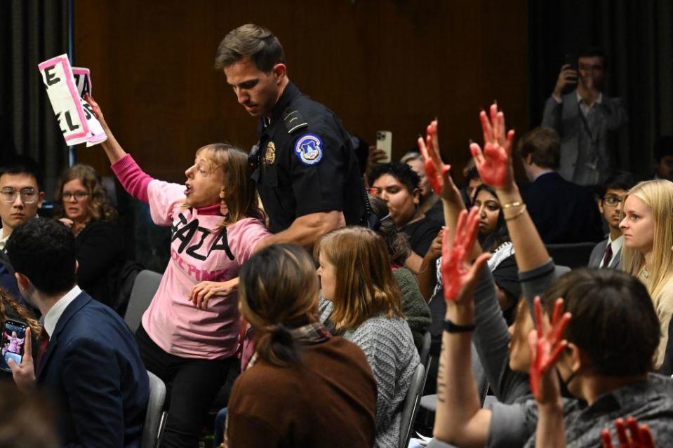 A protester is removed while others show painted hands as US Secretary of State Antony Blinken and Defense Secretary Lloyd Austin testify during a Senate Appropriations Committee hearing to examine the national security supplemental request, on Capitol Hill in Washington, DC, on Oct. 31, 2023. / Credit: SAUL LOEB/AFP via Getty Images