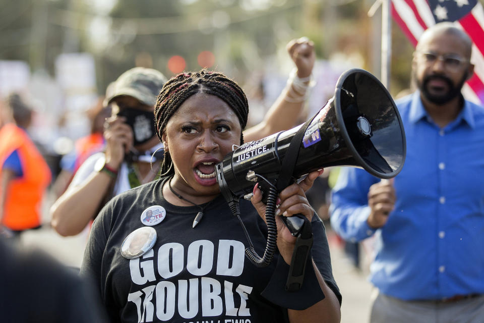 Civil rights activist Porchse Miller of Atlanta shouts into a megaphone during march that followed the Wall of Prayer event outside the Glynn County Courthouse, Thursday, Nov. 18, 2021, in Brunswick, Ga. The Rev. Al Sharpton organized the event after defense attorney Kevin Gough to objected to the presence of Black pastors in the courtroom. (AP Photo/Stephen B. Morton)