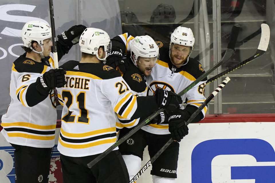 Boston Bruins teammates surround center Sean Kuraly (52) after Kuraly scored a goal during the third period of an NHL hockey game against the New Jersey Devils, Tuesday, May 4, 2021, in Newark, N.J. From the left are Bruins defenseman Mike Reilly (6). left-wing Nick Ritchie (21), Kuraly, and right-wing David Pastrnak (88). (AP Photo/Kathy Willens)