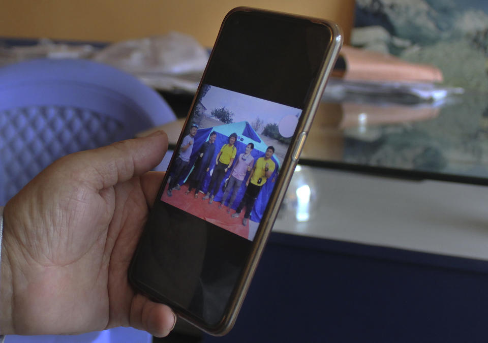 A Pakistani tour operator Haji Ghulam Muhammad, who arranged the trip of missing Korean climber Kim Hong Bin with others, views photos of them on his cell phone during an interview at his office in Skardu, a town in the Gilgit Baltistan region of northern Pakistan, Tuesday, July 20, 2021. The famous fingerless South Korean climber Kim Hong Bin fell into a crevasse and went missing after scaling the world's 14th one of the highest peaks in northern Pakistan and a search mission is being planned to trace him, a Pakistani mountaineering official said Tuesday. (AP Photo/M.H. Balti)