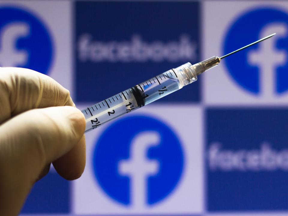 In this photo illustration a medical syringe seen with Facebook logo displayed on a screen in the background.