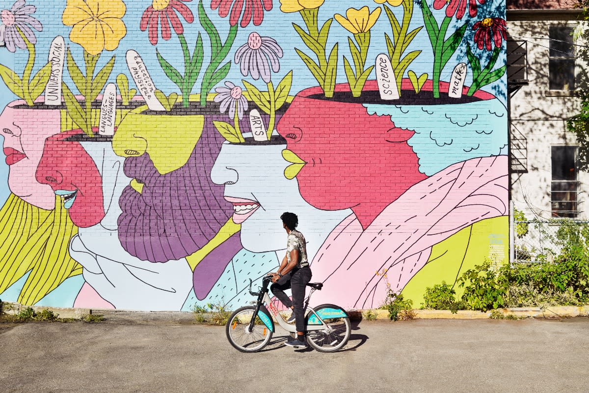 person riding a bike in front of colorful mural during spring in Montréal