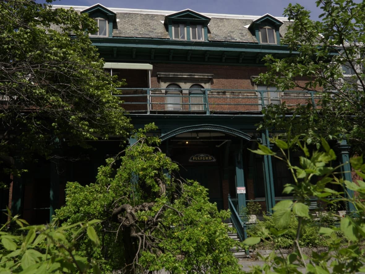 Overgrown gardens and shrubs surround Fulford Residence on Guy Street in downtown Montreal. After sitting vacant since 2021, Chez Doris has purchased the mansion, which gained heritage status in recent years. (Verity Stevenson/CBC - image credit)