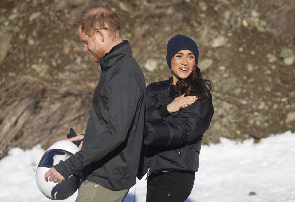 Prince Harry and Meghan Markle, the Duke and Duchess of Sussex, walk together after Harry slid down the track on a skeleton sled a second time while attending an Invictus Games training camp, in Whistler, British Columbia. Thursday, Feb. 15, 2024. (Darryl Dyck/The Canadian Press via AP)