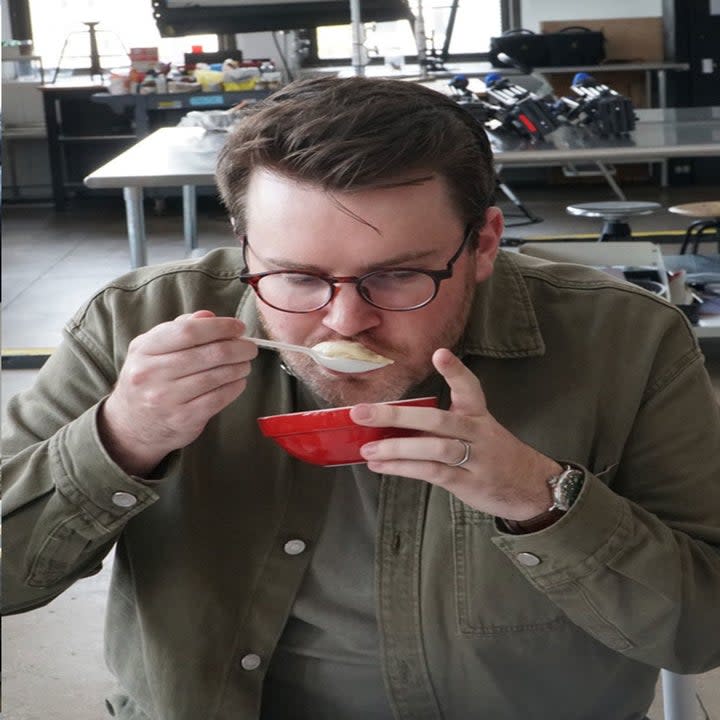 A man pensively eating a soup dumpling.