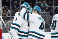 San Jose Sharks goaltender Devin Cooley, left, and defenseman Kyle Burroughs, right, hug after the team's win over the Seattle Kraken in an NHL hockey game Thursday, April 11, 2024, in Seattle. (AP Photo/John Froschauer)