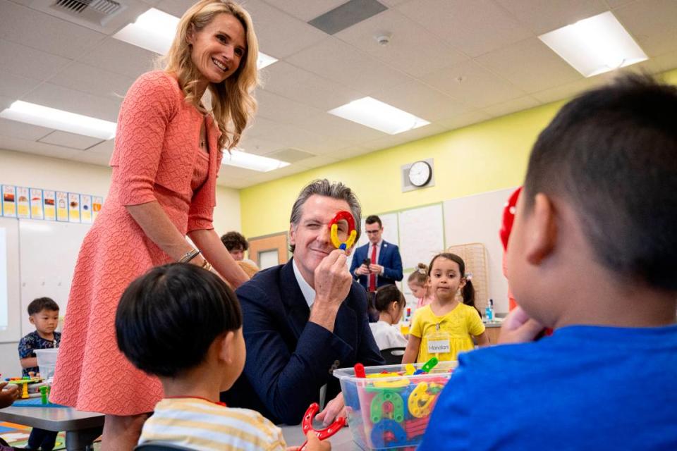 Gov. Gavin Newsom, joined by First Partner Jennifer Siebel Newsom, and a transitional kindergarten student peek at each other through plastic educational toys in August at Miwok Village Elementary School in Elk Grove, during an event to highlight the state’s plans to increase culturally competent instruction, nutrition initiatives, health care, counseling and before- and after-school programs.