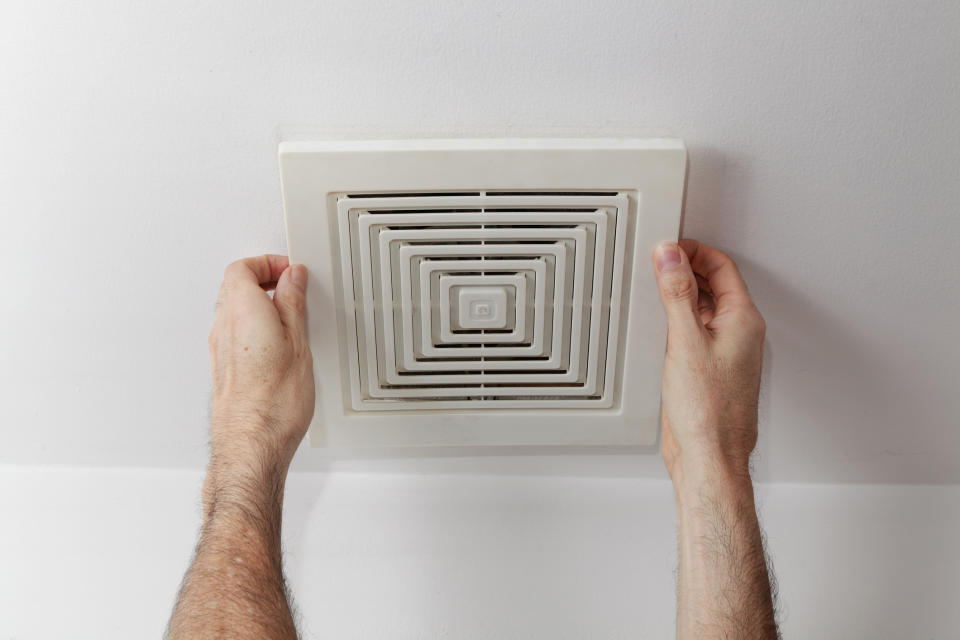 A person adjusting a bathroom vent