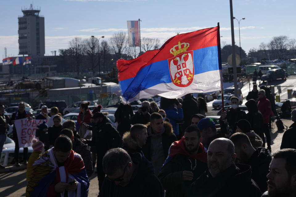 Fans wave a Serbian flag as Serbian tennis player Novak Djokovic arrives at the Nikola Tesla airport in Belgrade, Serbia, Monday, Jan. 17, 2022. Djokovic arrived in the Serbian capital following his deportation from Australia on Sunday after losing a bid to stay in the country to defend his Australian Open title despite not being vaccinated against COVID-19. (AP Photo/Darko Vojinovic)