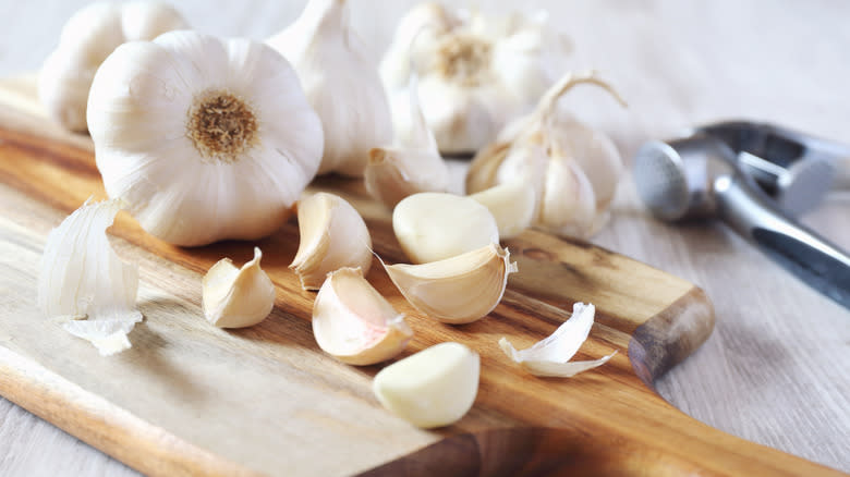 Unpeeled cloves of garlic on wooden cutting board