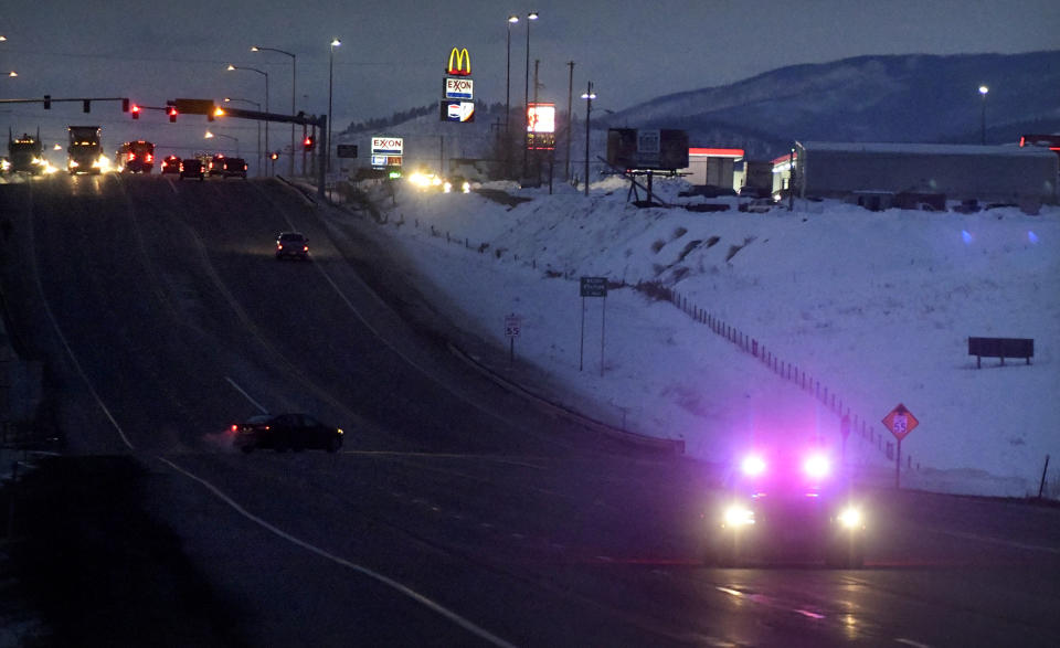 A law enforcement officer drives down Highway 93 during the manhunt for a suspect in a Montana Highway Patrol officer's shooting on Friday, March 15, 2019, in Missoula, Mont. Palmer, who was investigating an earlier shooting, was himself shot and critically injured early Friday after finding the suspect's vehicle, leading authorities to launch an overnight manhunt that ended in the arrest of a 29-year-old man, officials said. (Tommy Martino/The Missoulian via AP)