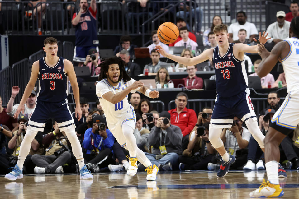 UCLA guard Tyger Campbell (10) passes the ball as Arizona guard Pelle Larsson (3) and Arizona forward Azuolas Tubelis (10) defend during the first half of an NCAA college basketball game in the championship of the Pac-12 tournament, Saturday, March 11, 2023, in Las Vegas. (AP Photo/Chase Stevens)