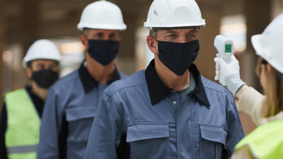 Un persona le toma la temperatura a unos trabajadores