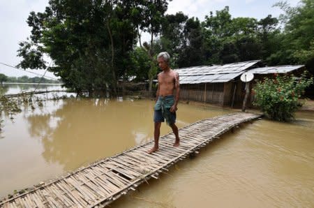 A man uses a makeshift bamboo bridge to cross a flooded area at a village in Nagaon district, in the northeastern state of Assam, India, June 19, 2018. REUTERS/Anuwar Hazarika
