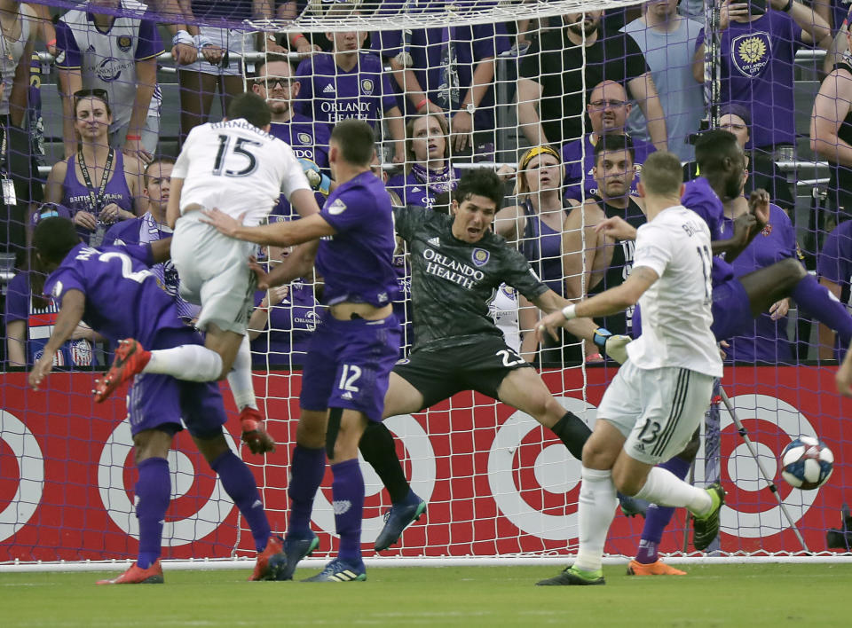 D.C. United's Steve Birnbaum (15) heads the ball past Orlando City goalkeeper Brian Rowe, second from right, to score a goal during the first half of an MLS soccer match, Sunday, March 31, 2019, in Orlando, Fla. (AP Photo/John Raoux)