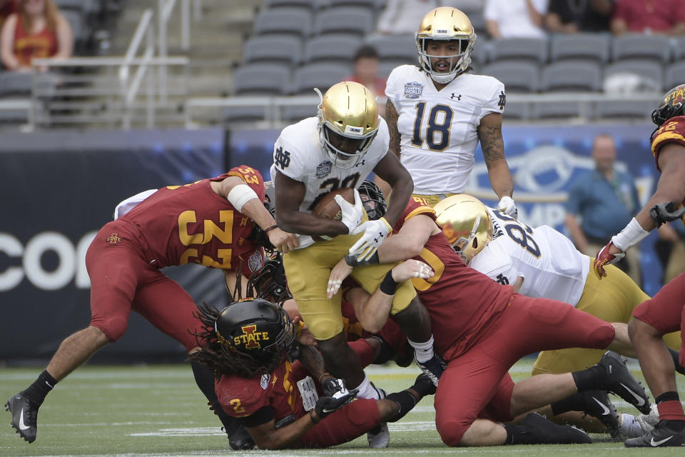 FILE - Notre Dame running back C'Bo Flemister (20) is tackled by Iowa State defensive back Braxton Lewis (33), defensive back Datrone Young (2) and linebacker Jared Gescheidler (40) after rushing for yardage during the second half of the Camping World Bowl NCAA college football game Saturday, Dec. 28, 2019, in Orlando, Fla. With all the success Notre Dame has enjoyed its last three seasons, amassing a 33-6 record under coach Brian Kelly, it has been the inability to run the football successfully in big games that has curtailed the championship hopes of the Fighting Irish. (AP Photo/Phelan M. Ebenhack, File)