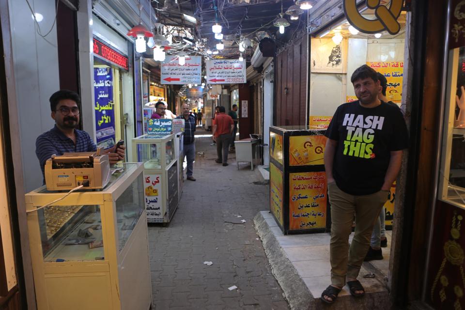 In this Wednesday, May 21, 2019, photo, money exchangers wait for customers at Shiite holy neighborhood of Kadhimiya's main market, Iraq. Many shop owners in the Shiite holy neighborhood of Kadhimiya, have seen their sales drop sharply over the past year since U.S. President Donald began reimposing sanctions on Iran, home to the largest number of Shiite Muslims around the world. (AP Photo/Khalid Mohammed)