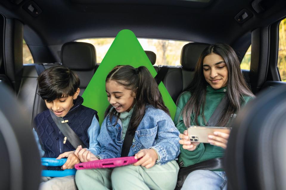 Children watching films on devices in the back of a car