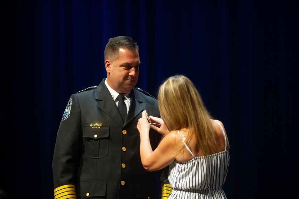 Rachel Noel, Paul Noel's wife, pins the chief badge to his jacket during the police chief swearing-in ceremony at the Knoxville Coliseum in Knoxville on Monday.