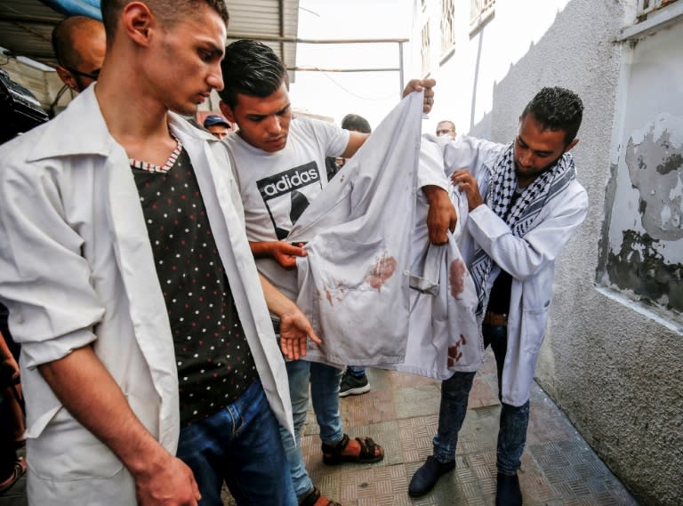 Colleagues of killed 21-year-old Palestinian volunteer medic Abdullah al-Qatati hold up his blood-stained white cloak during his funeral in the Gaza Strip on August 11, 2018, a day after he was killed during protests along the Israel-Gaza border