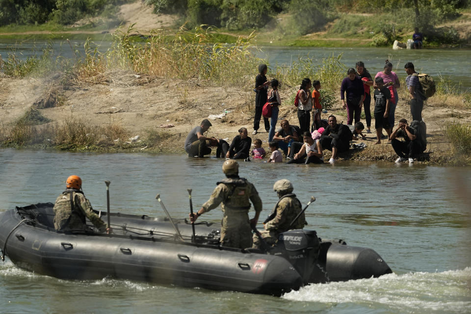 Guardsmen encourage migrants waiting on a sand bar to turn around as they attempt cross the Rio Grande from Mexico into the U.S., Saturday, Sept. 23, 2023, in Eagle Pass, Texas. (AP Photo/Eric Gay)