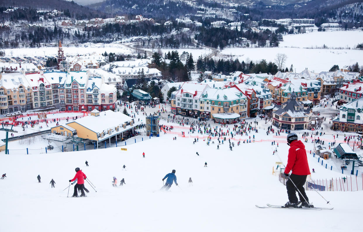 Mont-Tremblant, Canada - February 9, 2014:  Skiers and snowboarders are sliding down the main slope at Mont-Tremblant. Mont-Tremblant Ski Resort is acknowledged by most industry experts as being the best ski resort in Eastern North America.