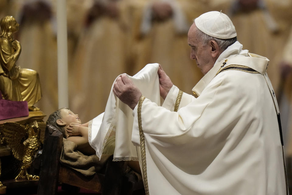 Pope Francis unveils a statue of Baby Jesus as he celebrates Christmas Eve Mass, at St. Peter's Basilica, at the Vatican, Friday Dec. 24, 2021. Pope Francis is celebrating Christmas Eve Mass before an estimated 1,500 people in St. Peter’s Basilica. He's going ahead with the service despite the resurgence in COVID-19 cases that has prompted a new vaccine mandate for Vatican employees. (AP Photo/Alessandra Tarantino)