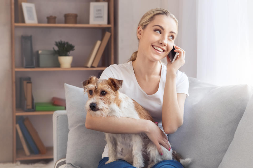 Young woman with dog at home phone call