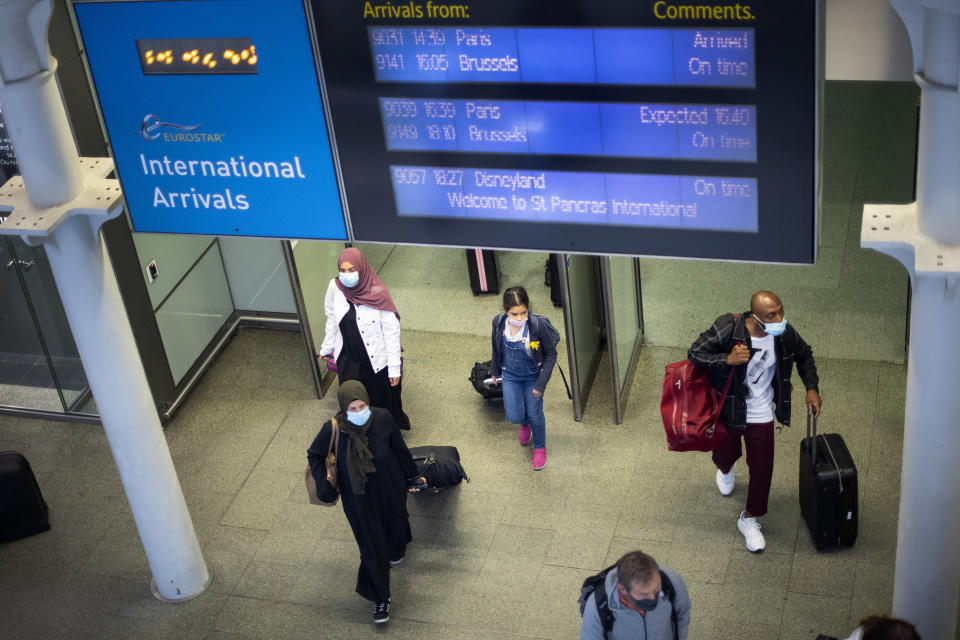 Travellers wearing face masks arrive from Paris to St Pancras Station in London after quarantine restrictions were imposed at 4am on Saturday morning.