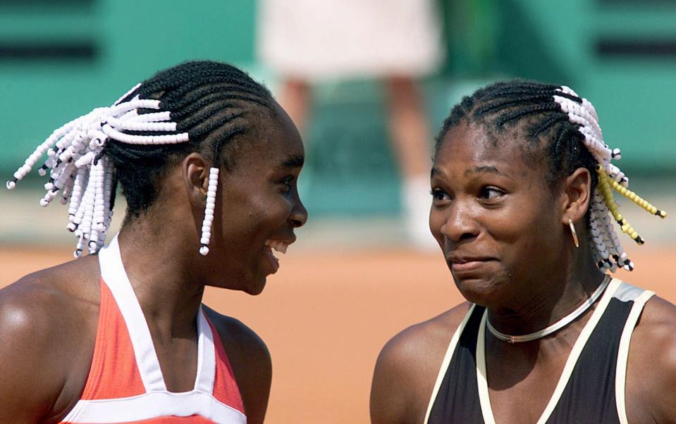 FILE - In this June 2, 1999, file photo, Venus Williams, left, and her sister Serena Williams share a light moment during their doubles tennis match against Els Callens of Belgium and Rita Grande of Italy at the French Open tennis tournament at Roland Garros stadium in Paris. (AP Photo/Laurent Rebours, File)