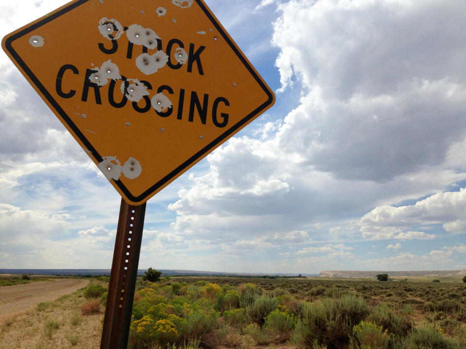 This Aug. 6, 2013 photo shows a bullet-ridden stock crossing sign on the rangeland north of Saratoga in Wyoming. Ranching remains heart and soul of the local economy. (AP Photo/Mead Gruver)