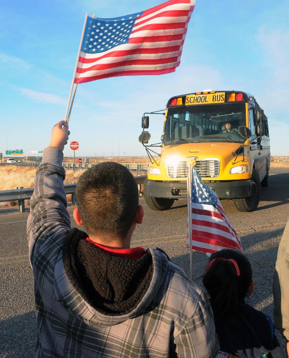 Supporters of Berrendo Middle School hold welcome backs signs and balloons while waving American flags and yellow ribbons, greet returning students, parents and teachers back to the school Thursday, Jan. 16, 2014, in Roswell, N.M. Two days after the shooting that involved three students and forced the evacuation and closing of the school. (AP Photo/Roswell Daily Record, Mark Wilson)