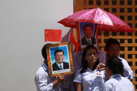 School boys hold portraits of Chinese President Xi Jinping during his welcoming ceremony in Phnom Penh, Cambodia October 13, 2016. REUTERS/Samrang Pring