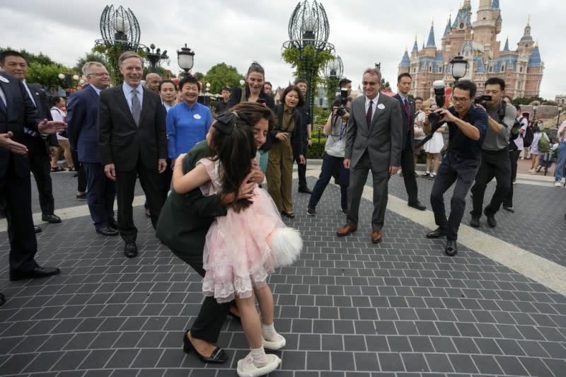 <cite>2023年8月30日，美國商務部長雷蒙多在上海迪士尼樂園遊覽擁抱一位小女孩。（美聯社）</cite>