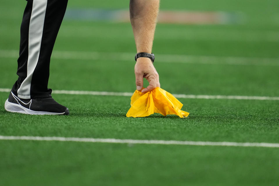 ARLINGTON, TEXAS - NOVEMBER 25: A close up view of a referee picking up a yellow flag between the Dallas Cowboys and the Las Vegas Raiders during an NFL game at AT&T Stadium on November 25, 2021 in Arlington, Texas. (Photo by Cooper Neill/Getty Images)