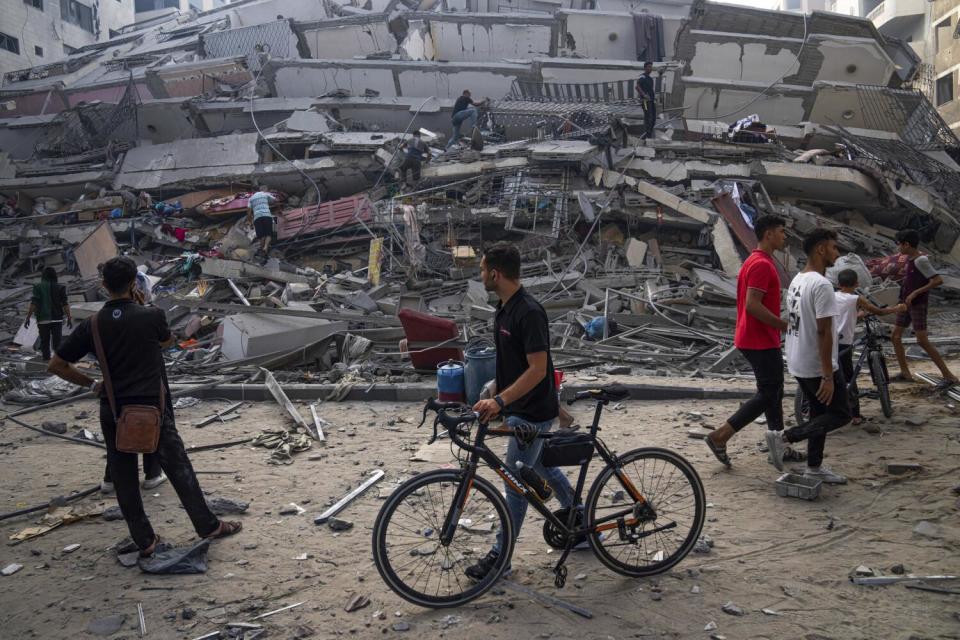 People looking at rubble of building destroyed by Israeli airstrike