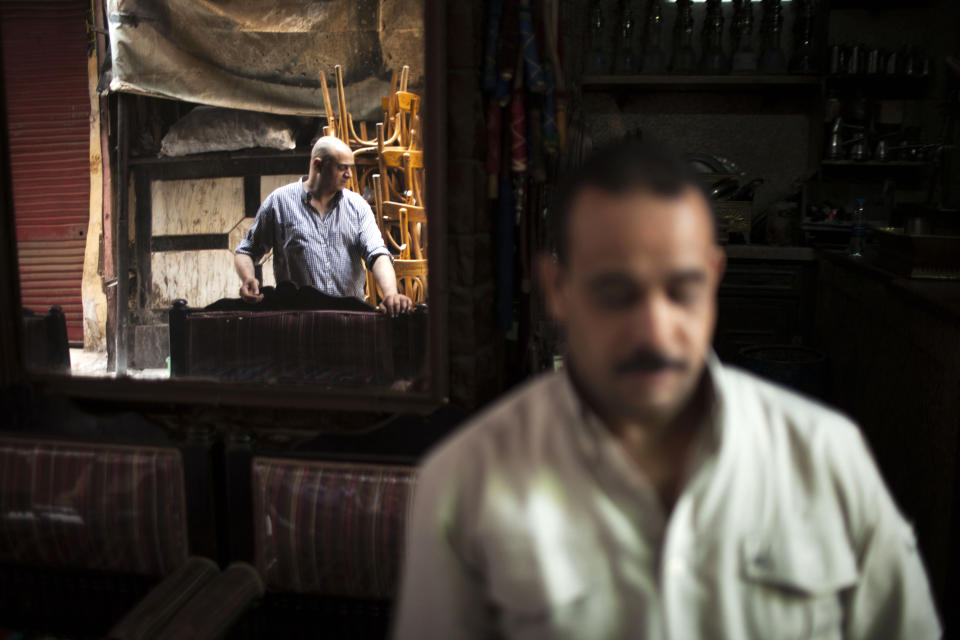 An Egyptian man is seen reflected on a mirror of his coffee shop in the Khan El-Khalili market, normally a popular tourist destination, in Cairo, Egypt, Wednesday, Aug. 21, 2013. Riots and killings that erupted across the country after the crackdown against followers of ousted President Mohammed Morsi have delivered a severe blow to Egypt's tourism industry, which until recently accounted for more than 11 percent of the country's gross domestic product and nearly 20 percent of its foreign currency revenues. (AP Photo/Manu Brabo)