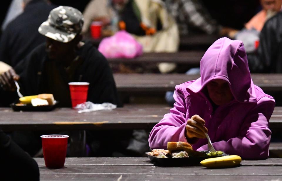 People gather for dinner with volunteers from the Under the Bridge Ministry, which serves food and supplies basic necessities to people in need at Sand Point Park in Titusville every Monday night.