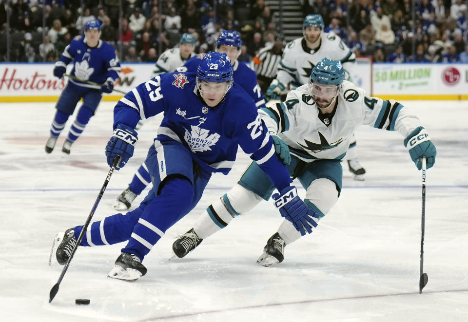 Toronto Maple Leafs forward Pontus Holmberg (29) protects the puck from San Jose Sharks defenseman Kyle Burroughs (4) during the second period of an NHL hockey game, Tuesday, Jan. 9, 2024 in Toronto. (Nathan Denette/The Canadian Press via AP)