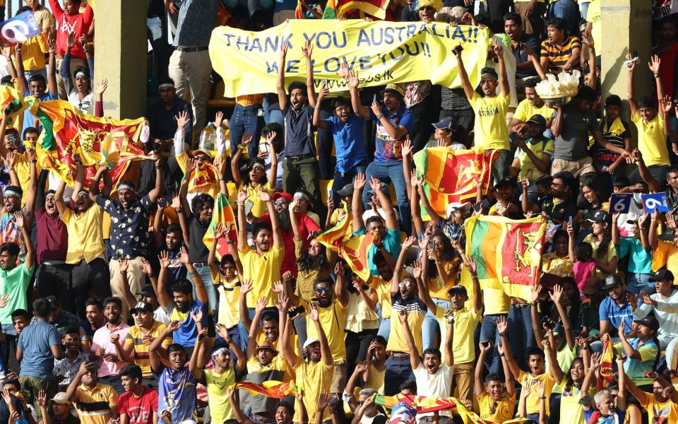 Sri Lankan cricket fans dressed in yellow while cheering and holding a banner thanks to the Australia cricket team