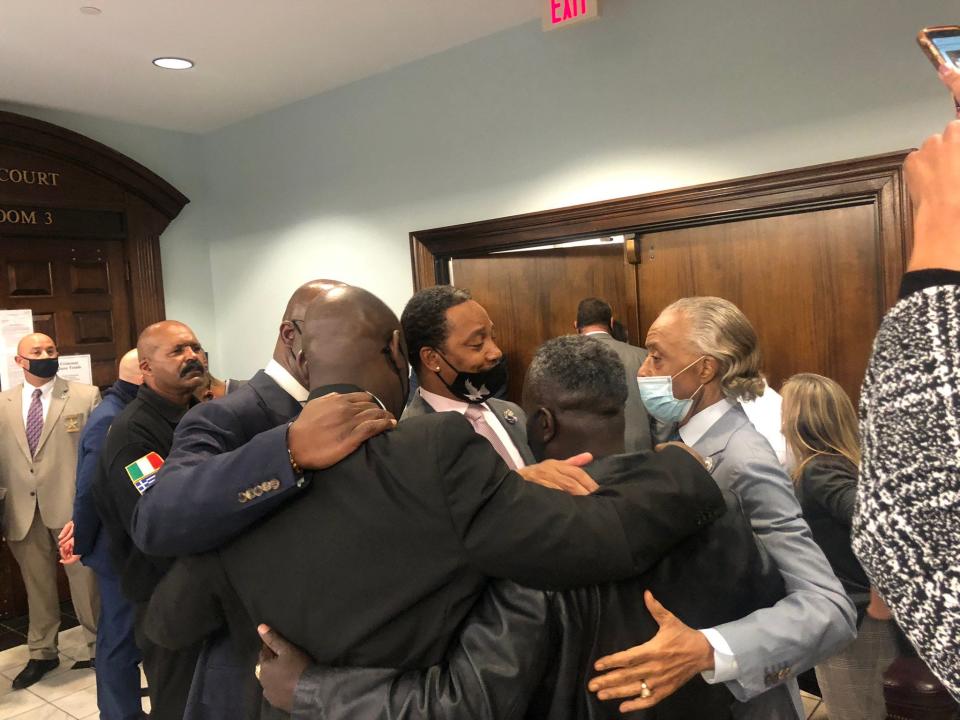 Ahmaud Arbery's father, Marcus, embraces lawyer Ben Crump and the Rev. Al Sharpton outside the courtroom.