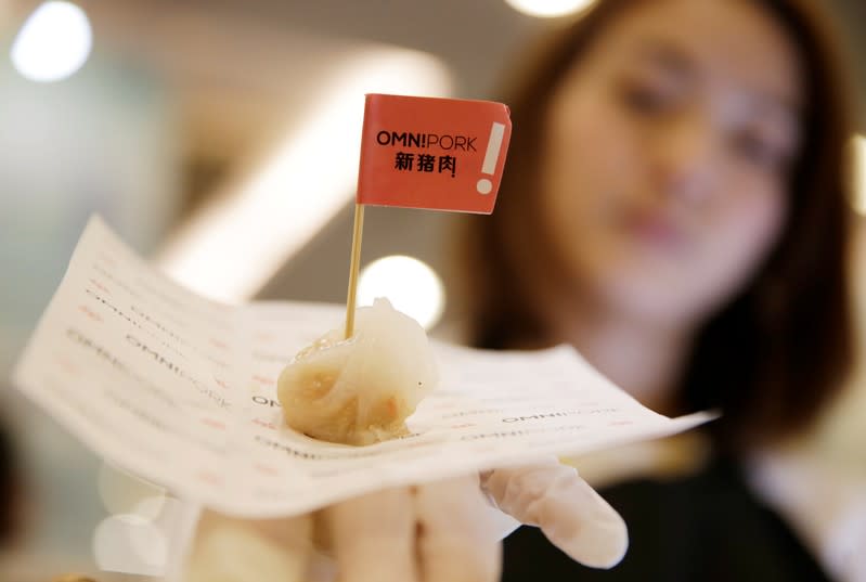 Cook displays a steamed dumpling with OmniPork plant-based meat at VeggieWorld fair in Beijing